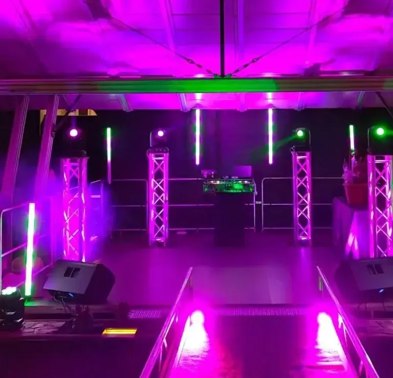 Bühne mit bunten Lichtern, Lautsprechern und DJ-Pult, bereit für eine Veranstaltung.