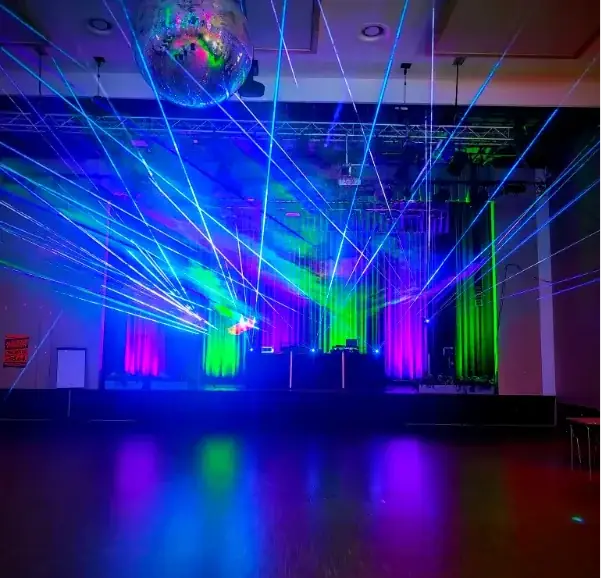 Bunte Laserstrahlen und Discokugel in einer festlichen Veranstaltungsumgebung.