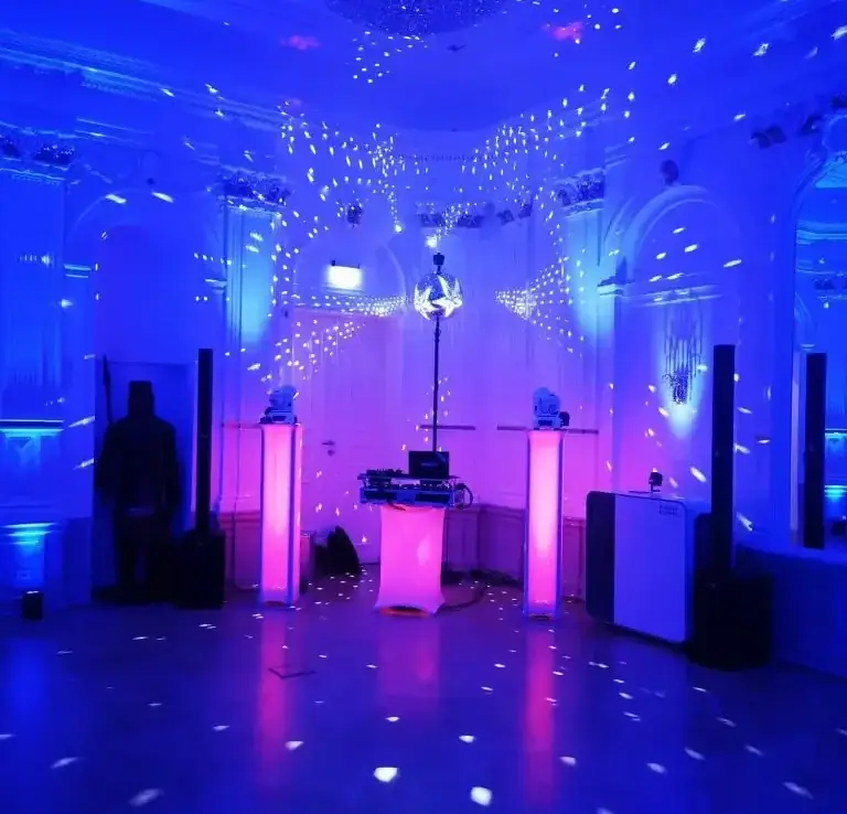 Bunte Lichter und Nebel in einem festlichen Raum mit DJ-Ausrüstung.