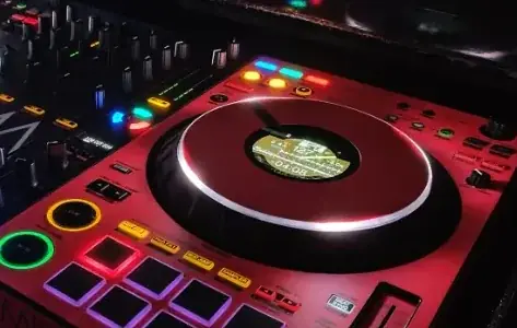 DJ-Pult mit bunten Lichtern, Plattenspieler und elektronischen Steuerungen.