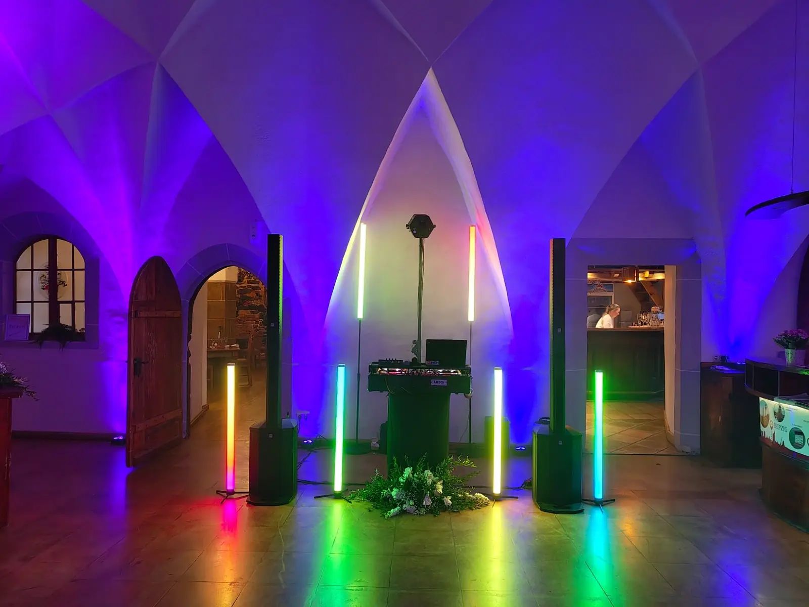Farbenfrohe Beleuchtung in einem Raum mit Lautsprechern und einem DJ-Pult.