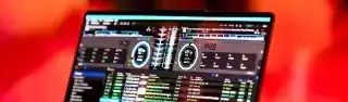 Laptop mit DJ-Software, umgeben von warmem, gefiltertem Licht und unscharfen Menschen.