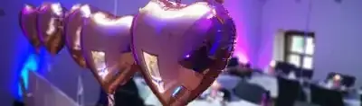 Roségoldene Herzballons hängen über einem festlich gedeckten Tisch.