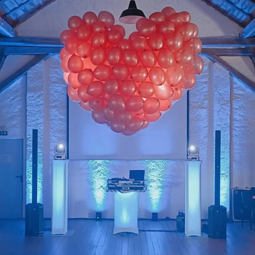 Rote Luftballons in Herzform hängen über einer festlich dekorierten Tanzfläche.