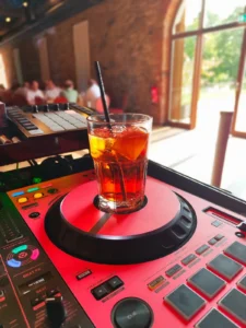 Ein Getränk in einem Glas auf einem DJ-Pult, im Hintergrund eine helle, einladende Umgebung. Photo by DJ Mirko Anders