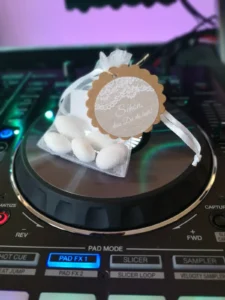 Ein weißes Geschenk mit einer goldenen Medaille und kleinen weißen Kugeln auf einem DJ-Pult. Photo by DJ Mirko Anders