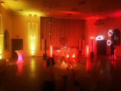 Festlich dekorierter Raum mit rotem und gelbem Licht, liebevoll eingedeckten Tischen. Photo by DJ Mirko Anders