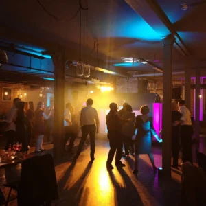 Menschen tanzen in einem beleuchteten Veranstaltungsraum mit Nebel und bunten Lichtern. Photo by DJ Mirko Anders