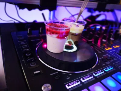 Zwei Dessertbecher stehen auf einem DJ-Controller in buntem Licht. Photo by DJ Mirko Anders