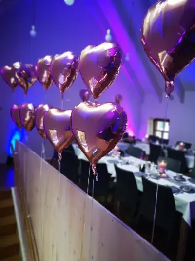 Roségoldene Herzballons Roségoldene Herzballons hängen über einem festlich gedeckten Tisch.
