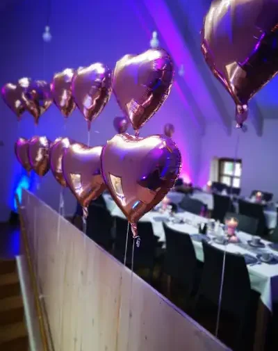 Roségoldene Herzballons Roségoldene Herzballons hängen über einem festlich gedeckten Tisch.