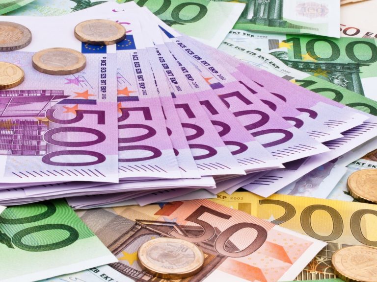 Bunt gemischte Euro-Banknoten und Münzen auf einem Tisch.