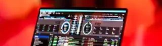 DJ Mirko Anders – Hochzeit Laptop mit DJ-Software, umgeben von warmem, gefiltertem Licht und unscharfen Menschen.